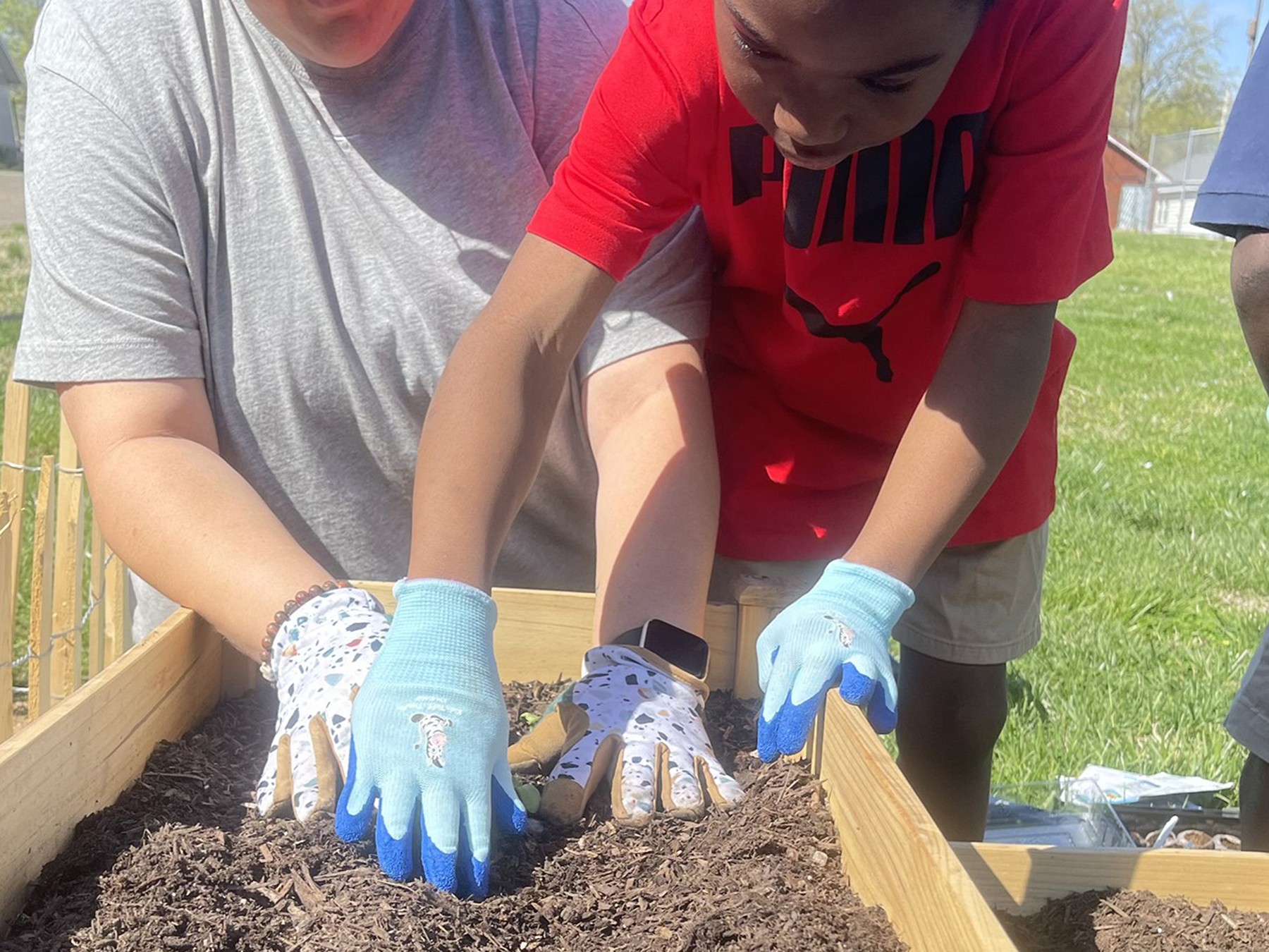 A youth member planting in our garden alongside a staff member.