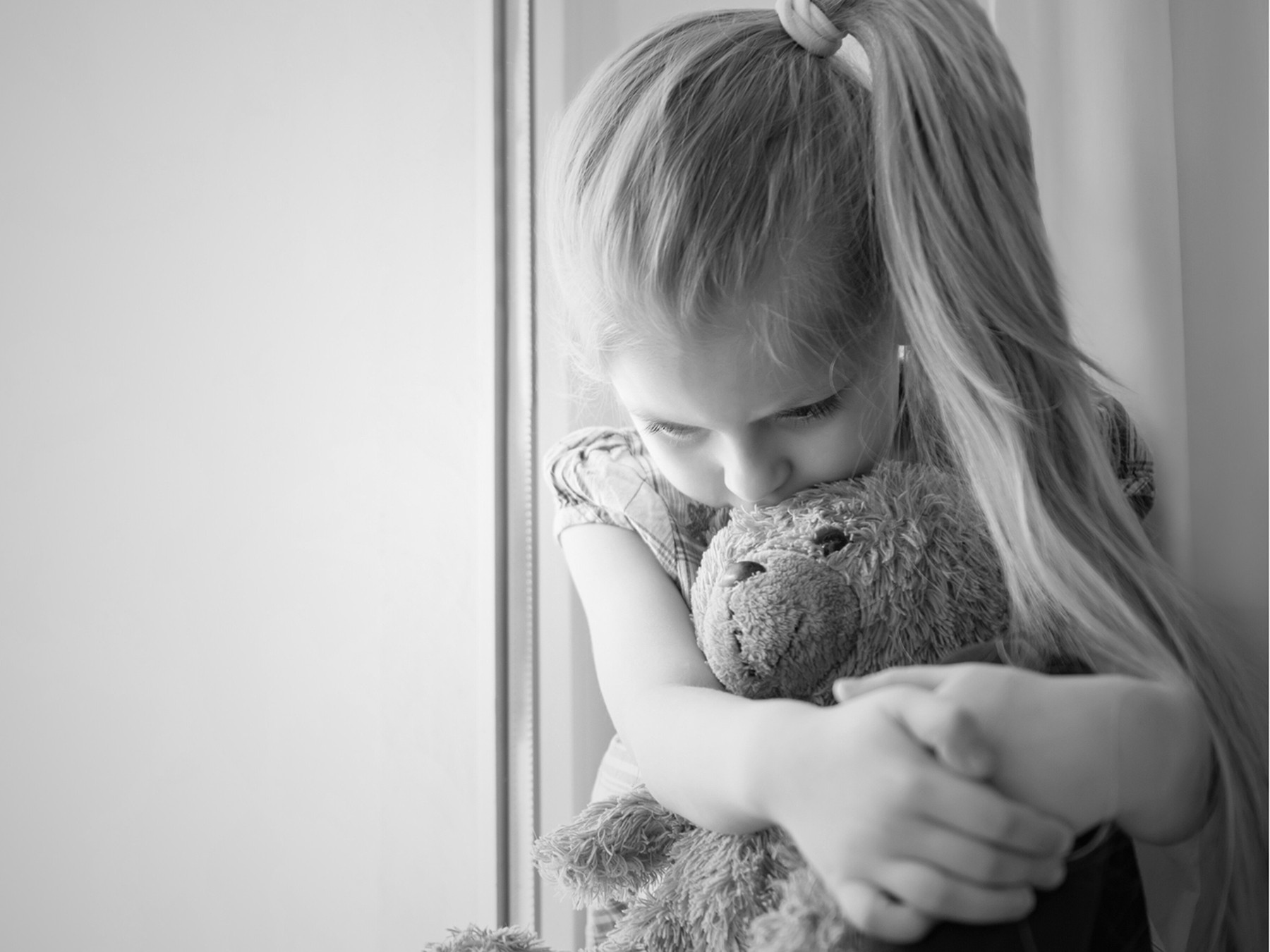 A young girl sits with stuffed teddy bear.