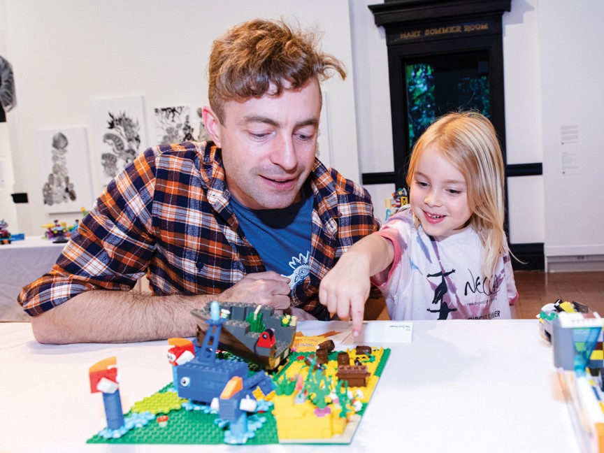 A father and daughter check out a LEGO sculpture at the museum. Impact