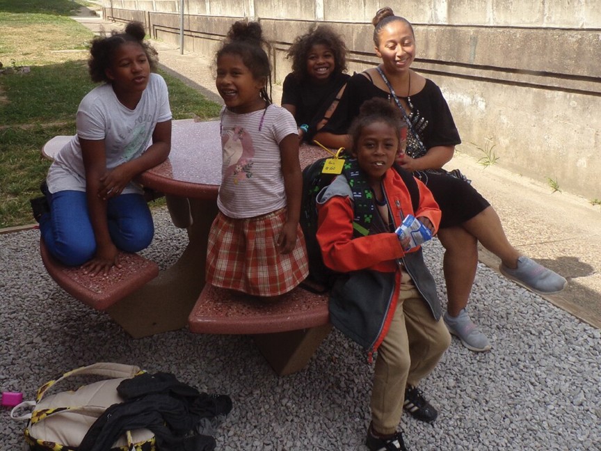 Mother and children who were being housed in our emergency shelter sitting at our new picnic table waiting for the school bus. Impact