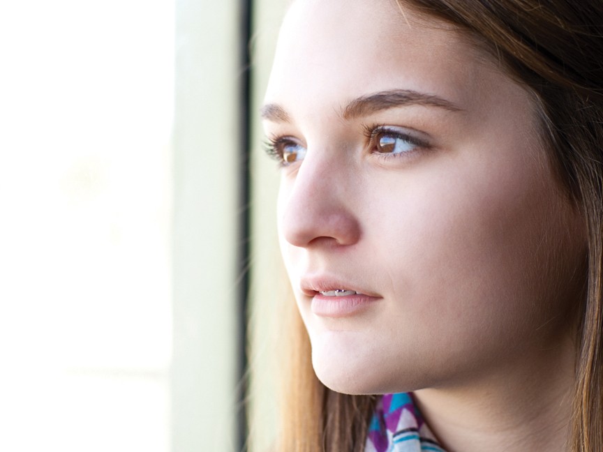 Photo of a teen witness/survivor of domestic violence looking out of the window. Impact