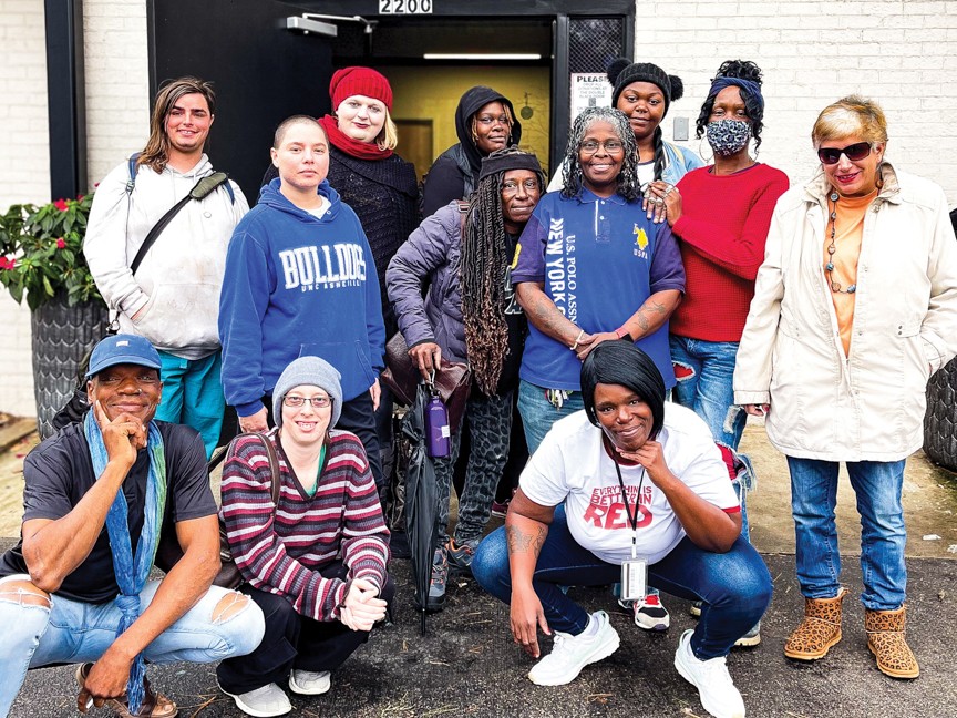 A group of women including clients, volunteers, and staff of the Women's Center posing outside of our front door. Impact