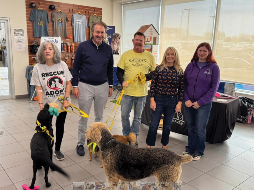 Jim Riley and Safe Haven representatives pose with two adoptable dogs and Jim's dog, Summer, during Riley Subaru's October 2024 adoption event. The event helped several pets find homes and raised awareness in Dubuque. Impact