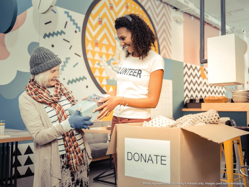Two Pillars clients smile outside their new affordable home. Impact