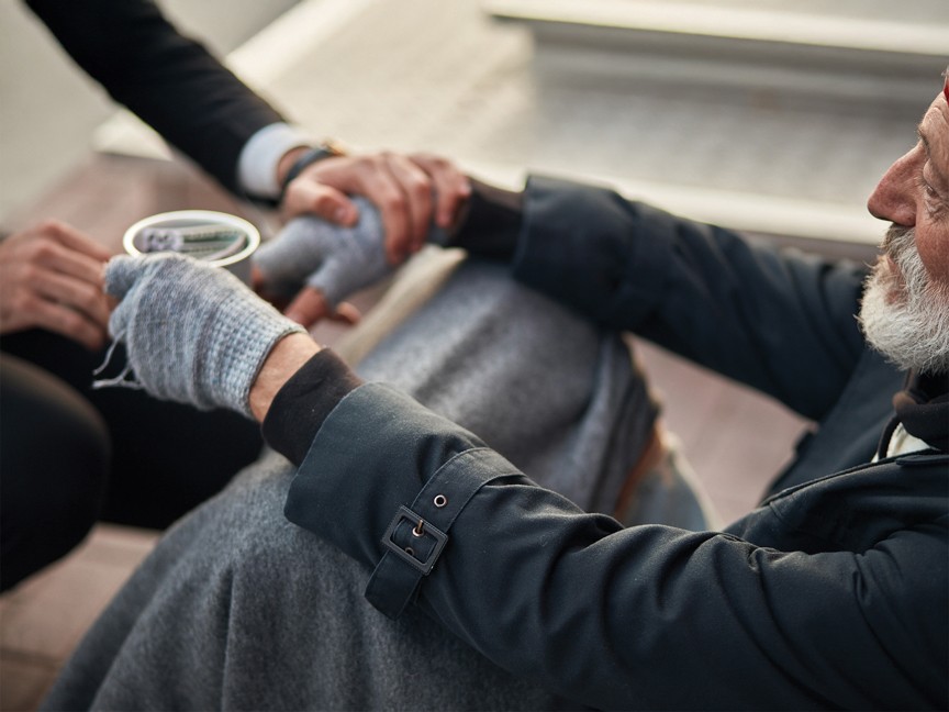 Person offers homeless man a helping hand, kindness, and support. Impact