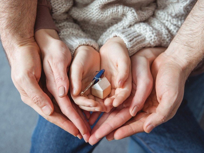A family of hands with representation of a new home. Impact