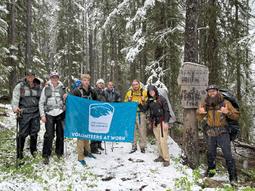 Volunteers braving a late Spring snowstorm as they pass the boundary into the Scapegoat Wilderness (part of the Bob Marshall Wilderness Complex) to clear a backcountry trail of seasonal blowdown with crosscut saws. Impact