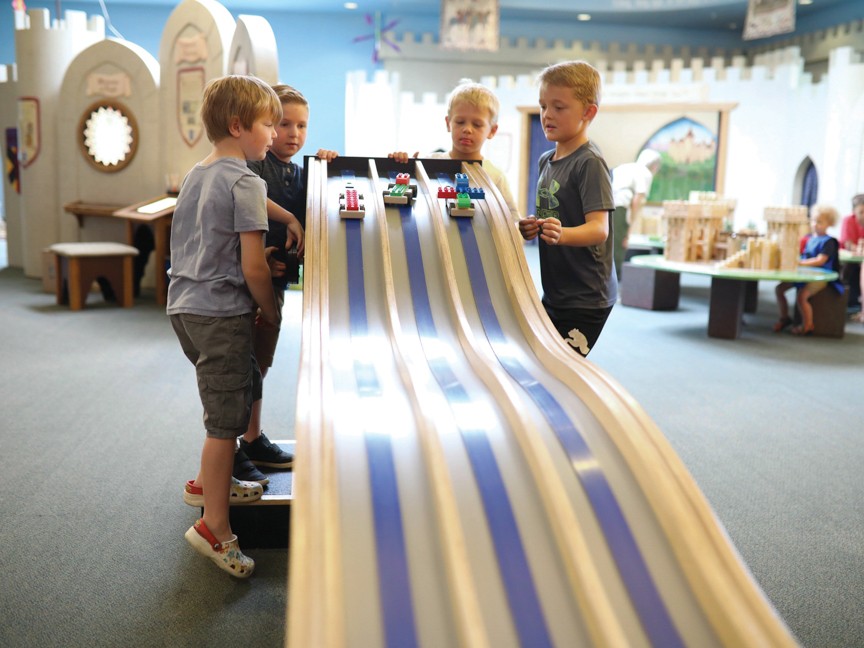 A group of four young boys have just launched the Lego cars they've assembled. The cars are headed down the Subaru Gravity Race Track and times will appear above each car as it crosses the finish line. Impact
