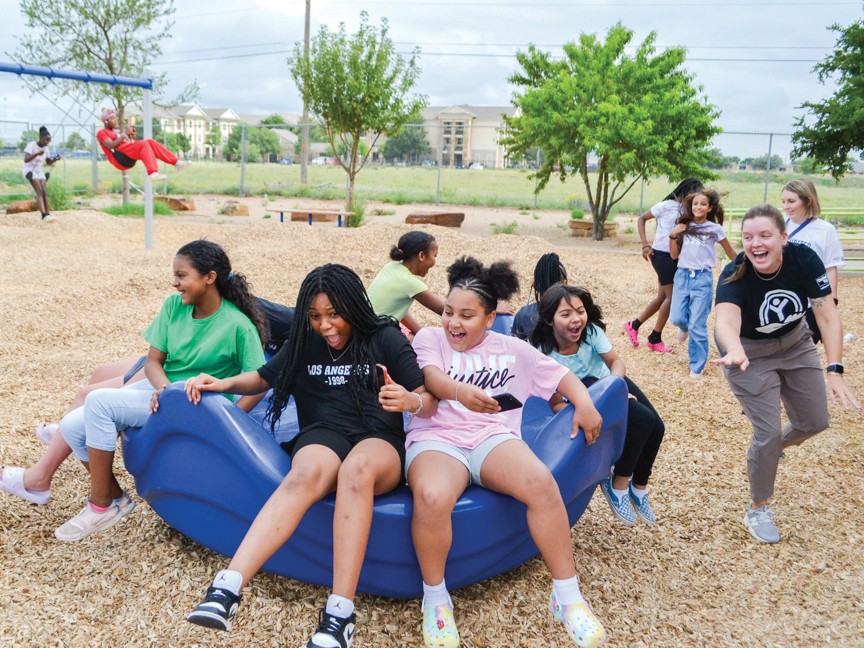 Lubbock Area United Way volunteers playing with children on playground. Impact