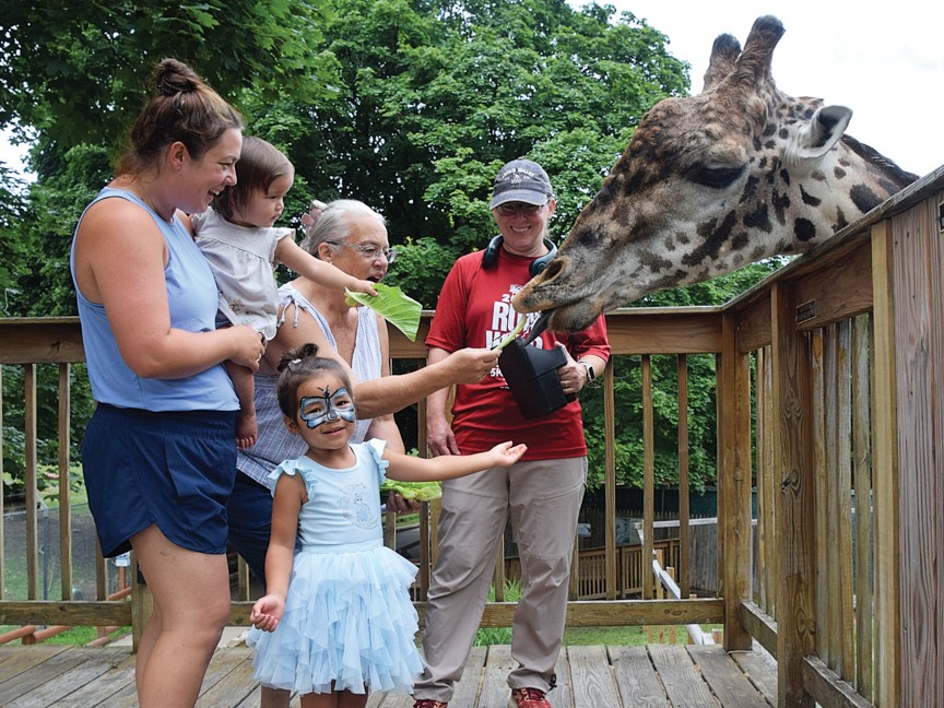 A family supporting conservation of endangered species while feeding a Masai Giraffe lettuce during an interactive experience at Lehigh Valley Zoo. Impact