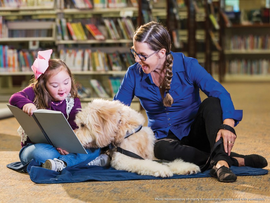 Laura and Houston Puppy Leader Schuyler Morris sit on a bench with working guide dog Steiner sitting between them. Steiner is Laura's new partner. Impact