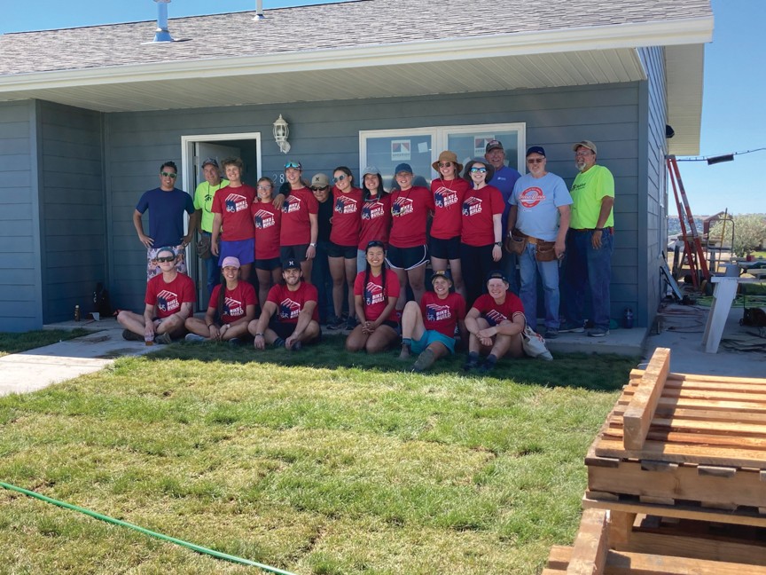Habitat for Humanity volunteers in front of a completed home. Impact