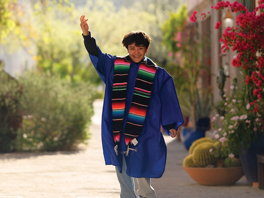 A YOTO youth celebrating their 2025 high school graduation by tossing their cap in the air. Impact